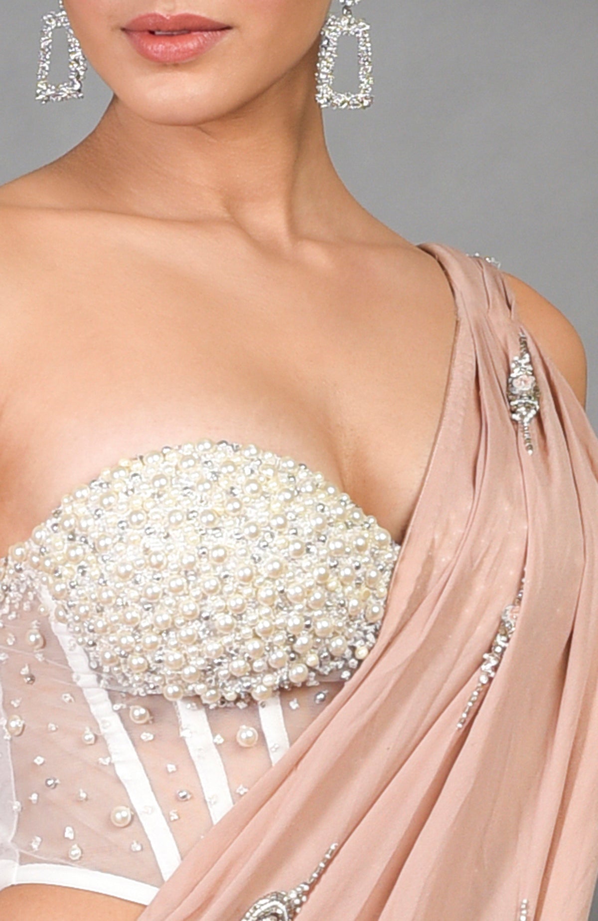 A woman models a pearl-embroidered corset and a nude pre-draped saree with embellishments.