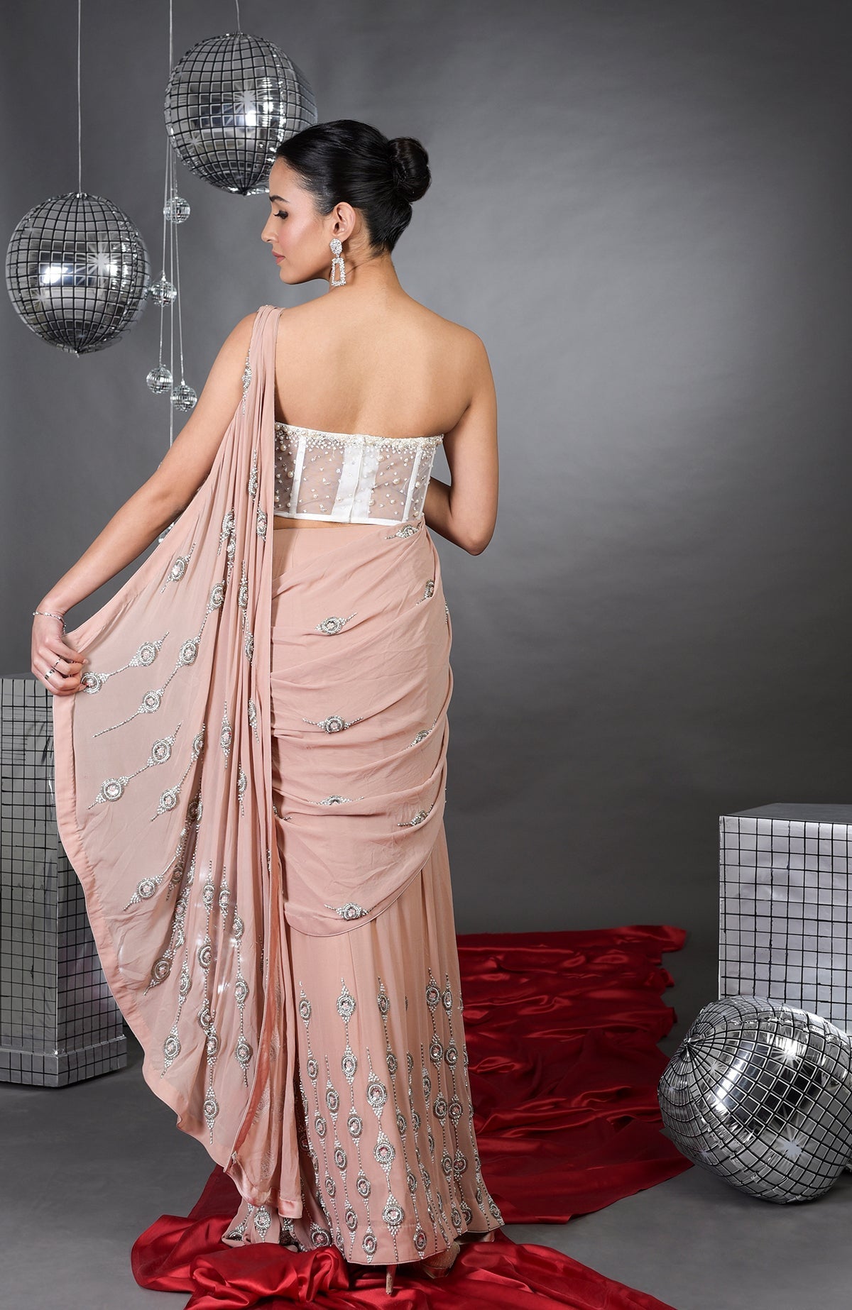 A woman models a nude pre-draped saree with a white embroidered corset.
