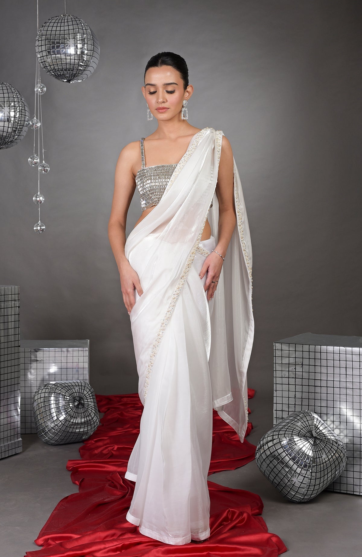 A woman models a white saree with a pearl-beaded border and a silver crystal bustier.