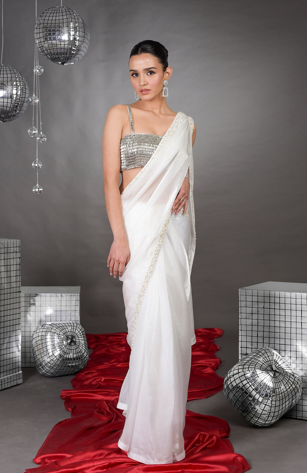 A woman models a white pearl-beaded saree with a silver crystal bustier.