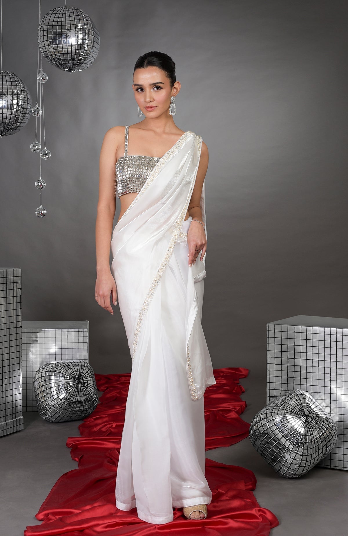 A woman models a white pearl-beaded saree with a silver crystal bustier.