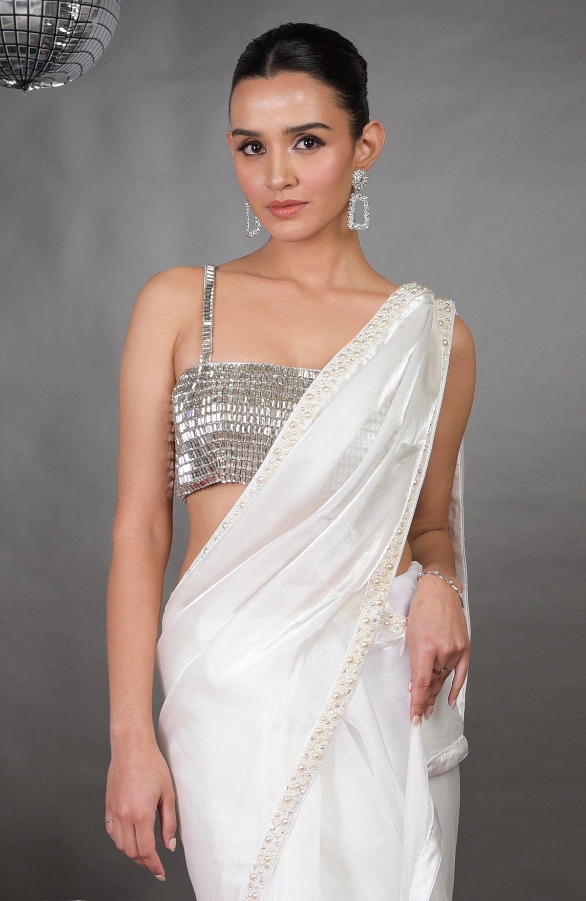 A woman models a white saree with pearl beading and a silver crystal bustier.