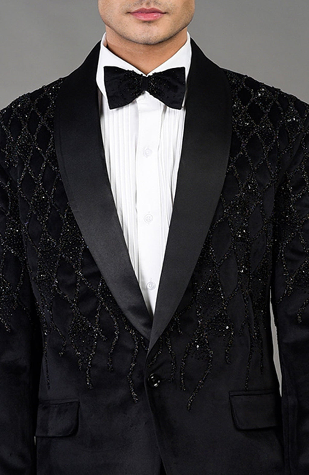 Black velvet tuxedo with beaded embroidery, white shirt, and black bow tie.