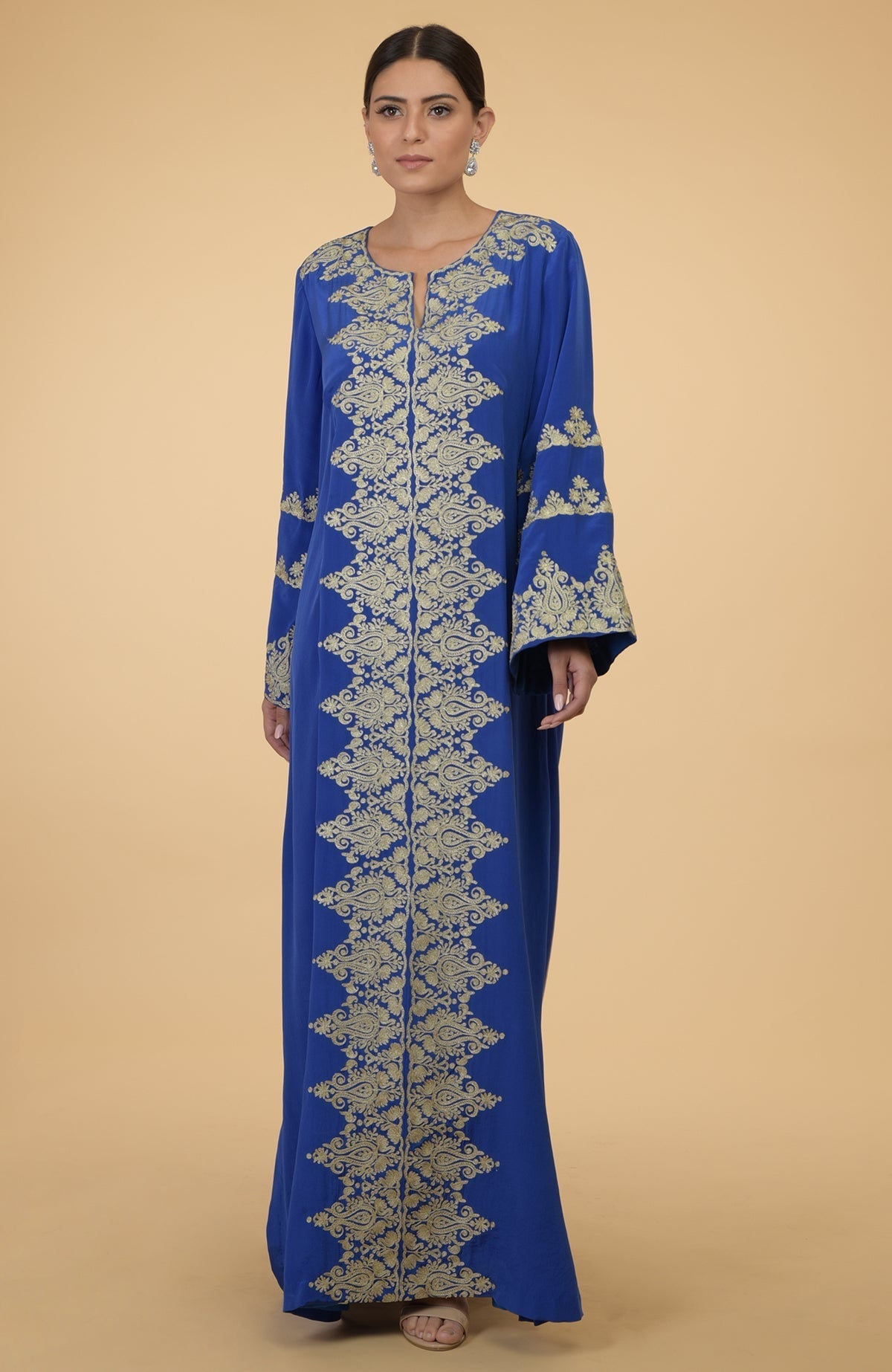 A woman models a cobalt blue kaftan with gold Kashmir embroidery.