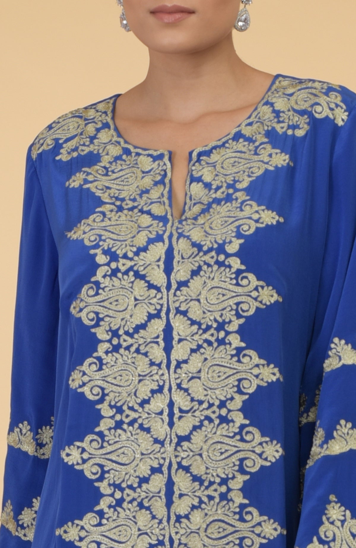 A woman models a cobalt blue silk crepe kaftan with gold Kashmir embroidery.