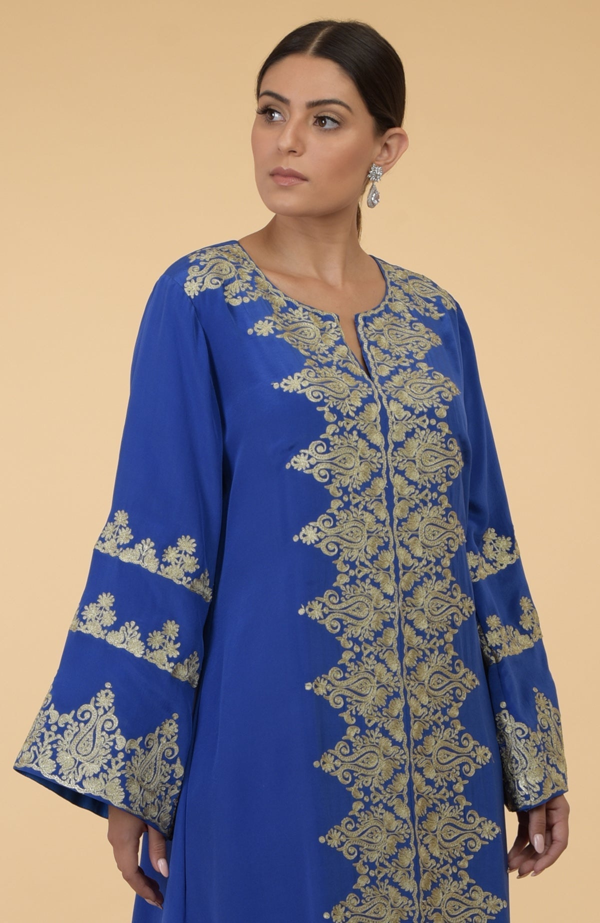 A woman models a cobalt blue kaftan with gold Kashmir embroidery.