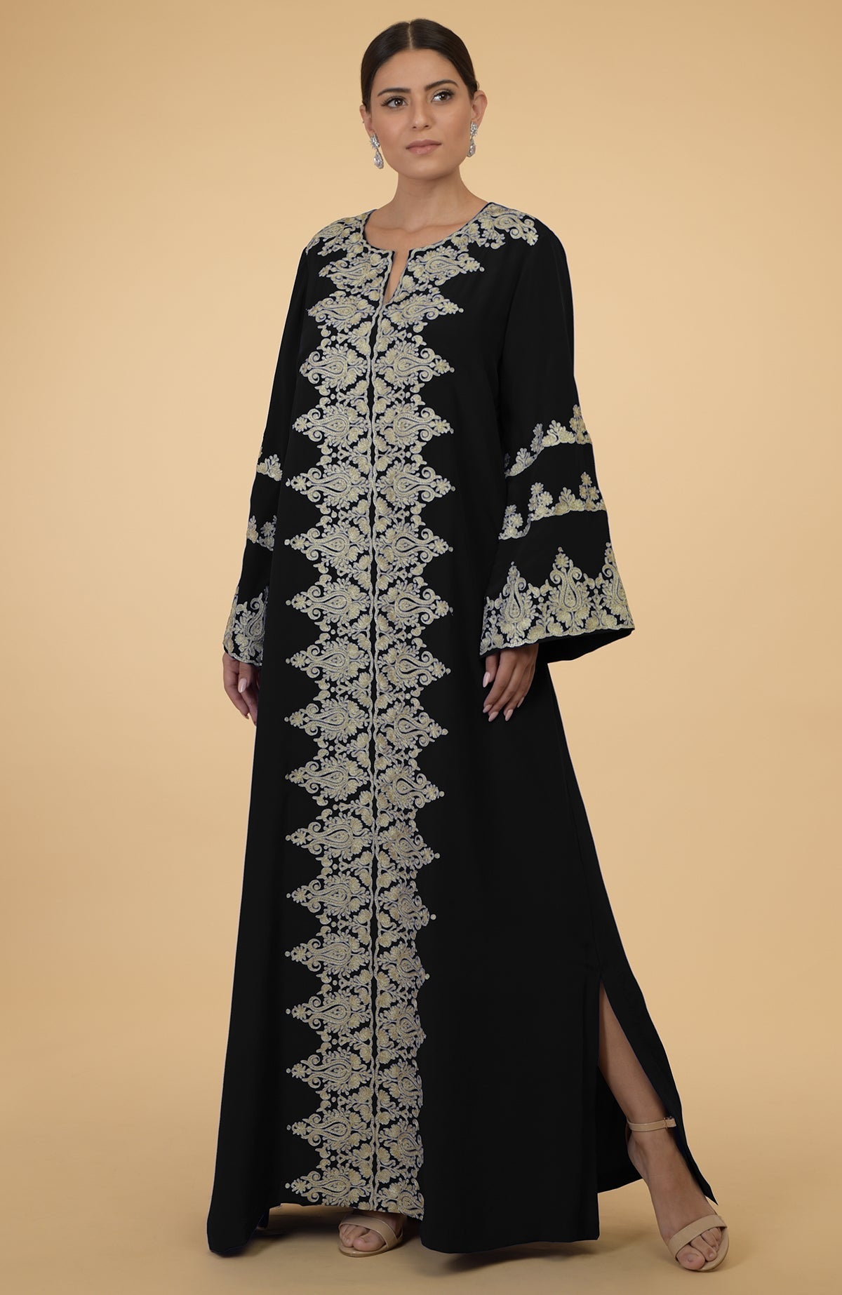 A woman models a black kaftan with gold Kashmir embroidery and side slits.
