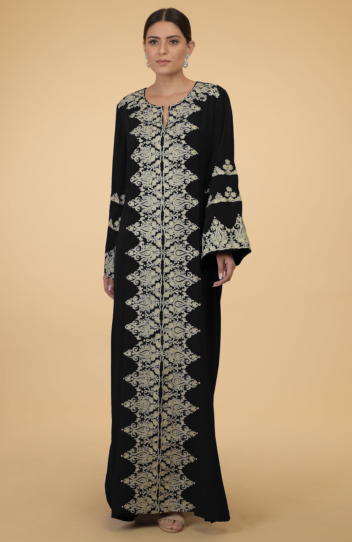 A woman models a black kaftan with gold Kashmir-inspired embroidery.