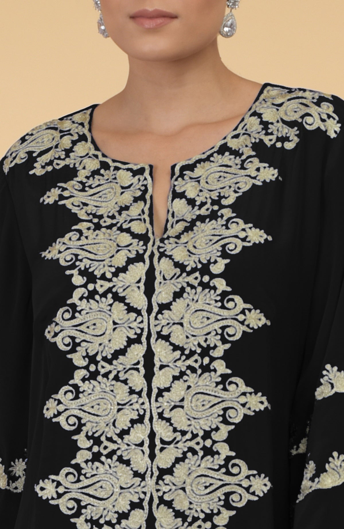 A woman models a black kaftan with intricate gold Kashmir embroidery around the neckline.