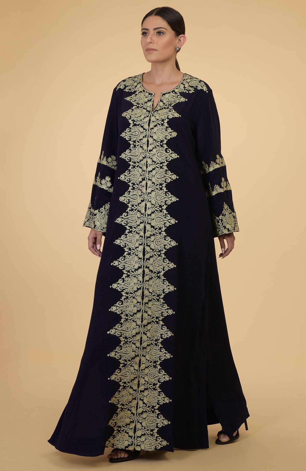 A woman models a midnight blue kaftan with gold Kashmir embroidery.