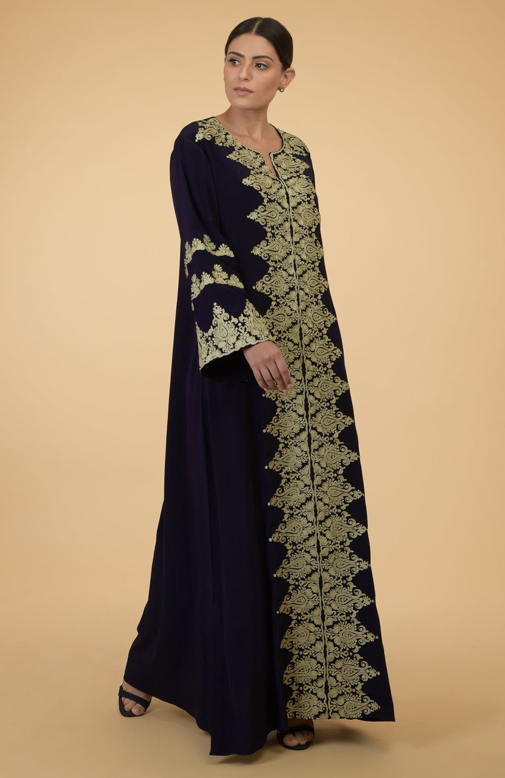 A woman models a midnight blue kaftan with gold Kashmir embroidery.