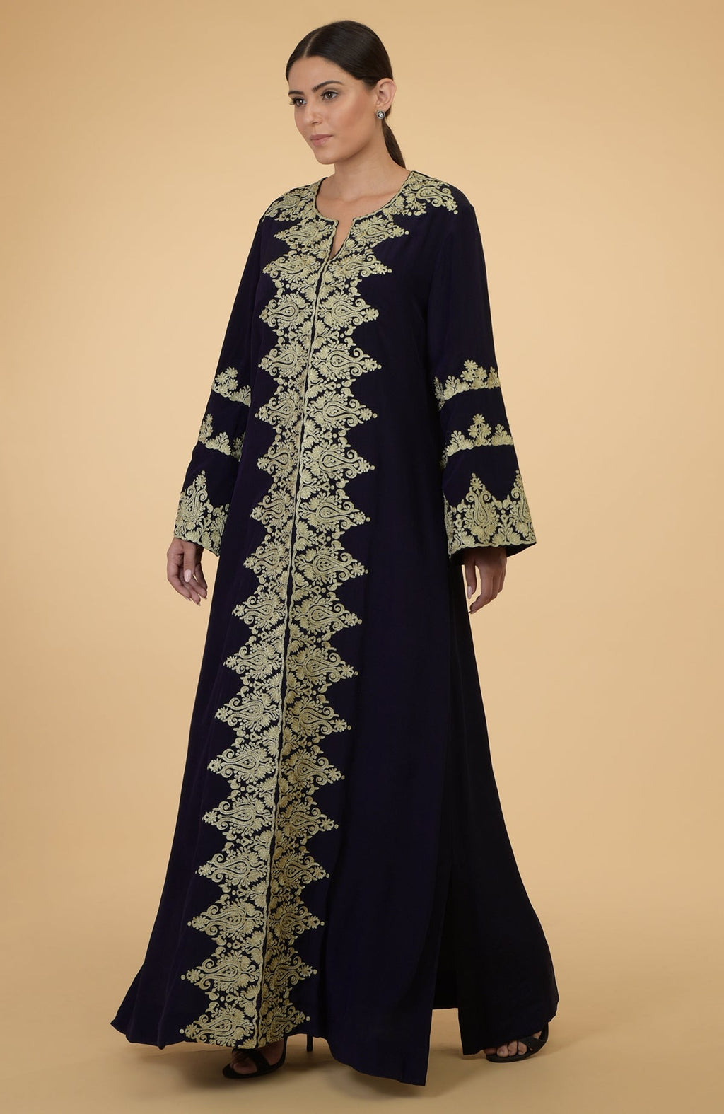 A woman models a midnight blue kaftan with gold Kashmir embroidery.