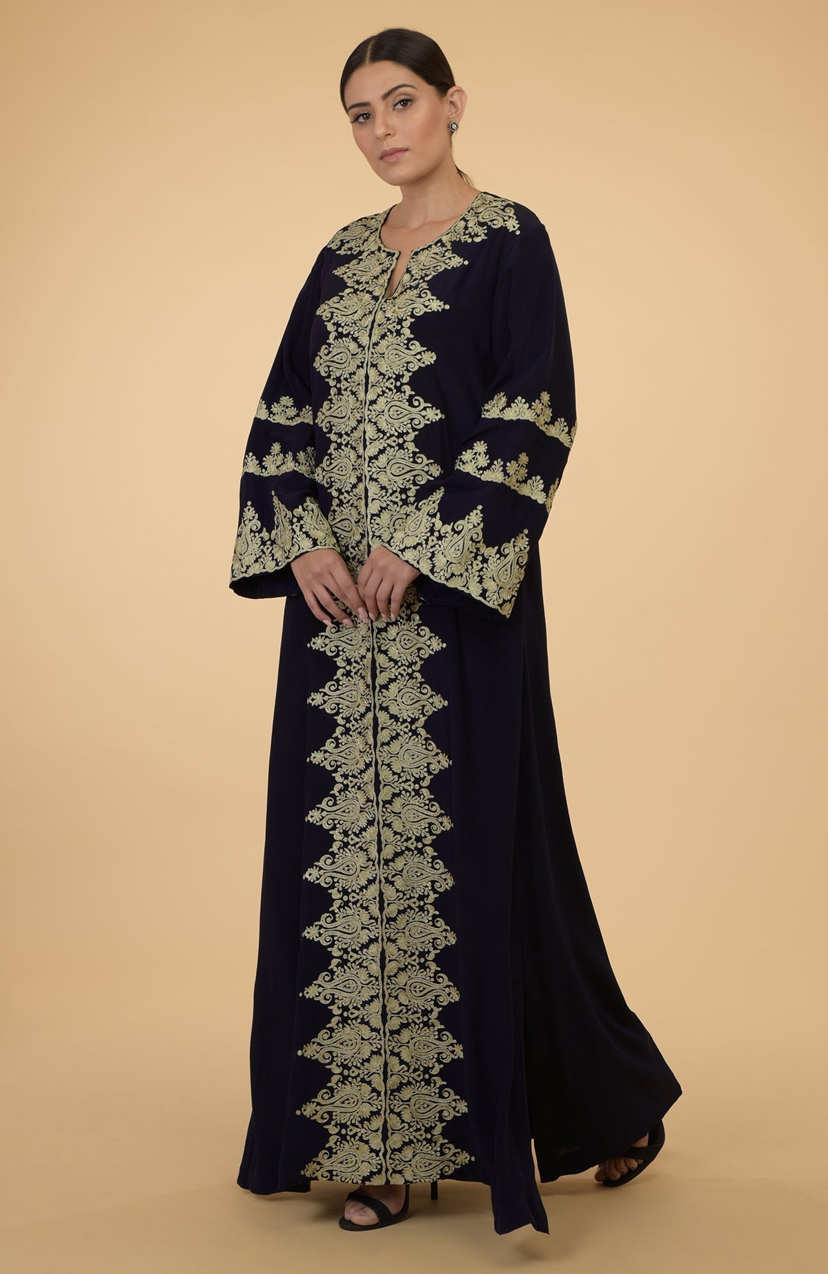 A woman models a midnight blue kaftan with gold Kashmir embroidery.