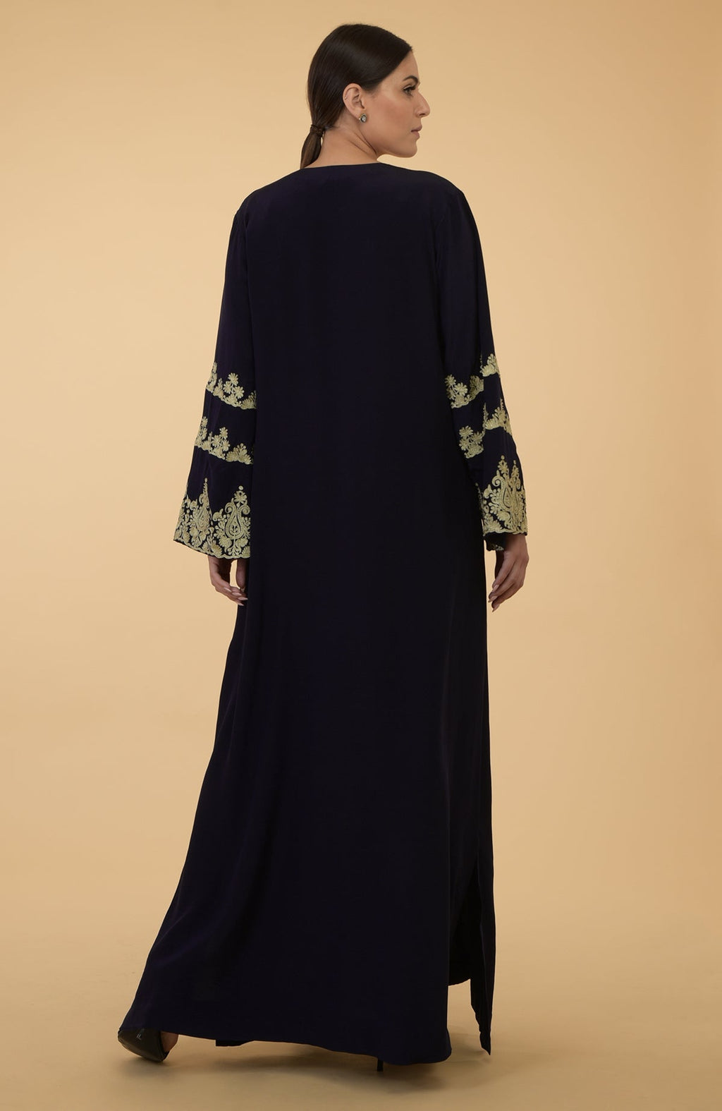 A woman models a midnight blue kaftan with gold Kashmir embroidery on the sleeves.