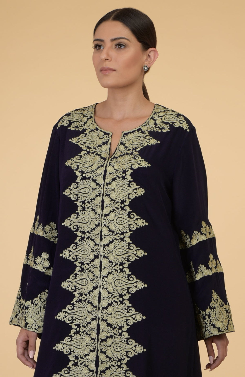 A woman models a midnight blue kaftan with gold Kashmir embroidery.