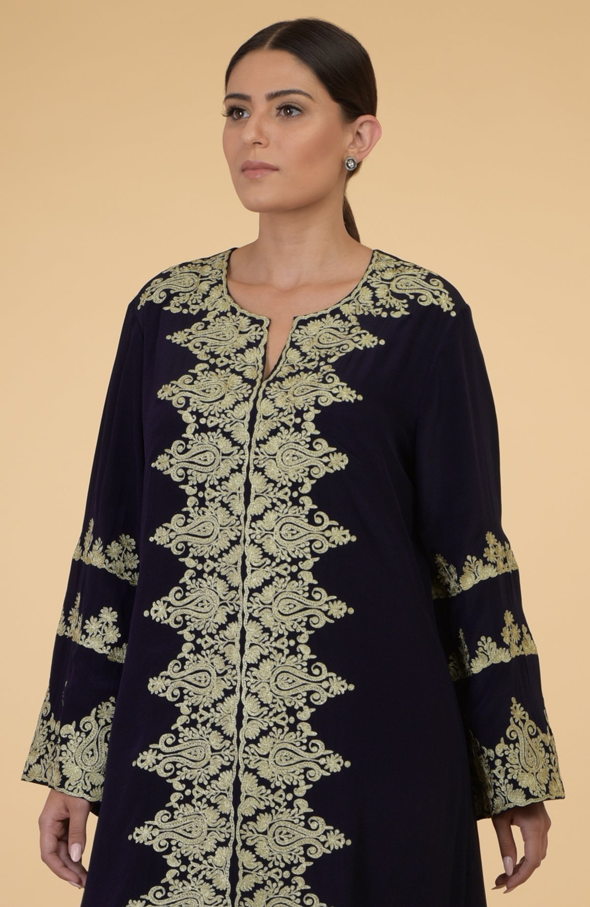 A woman models a midnight blue kaftan with gold Kashmir embroidery.