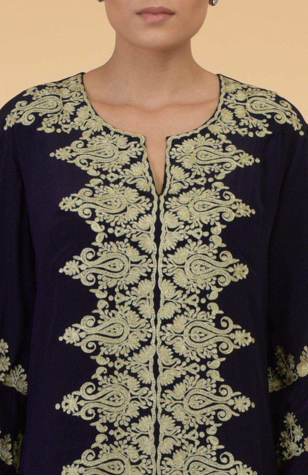 A woman models a midnight blue kaftan with gold Kashmir embroidery.