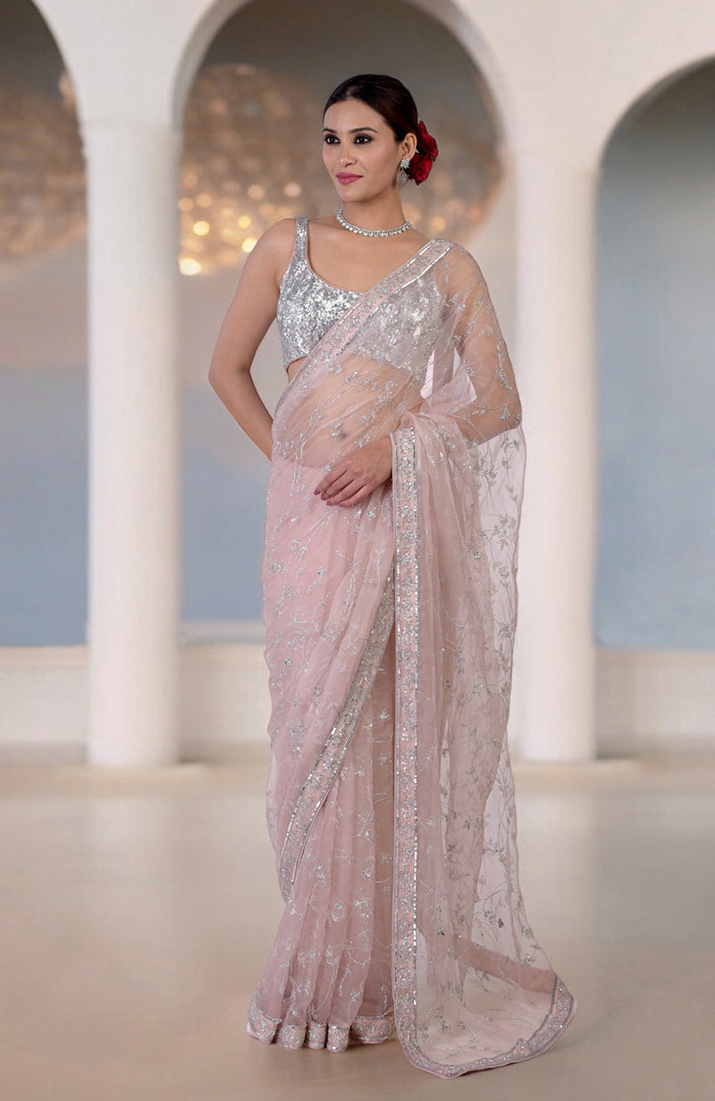 An elegant woman models an oyster pink saree with silver bead and sequin embroidery.