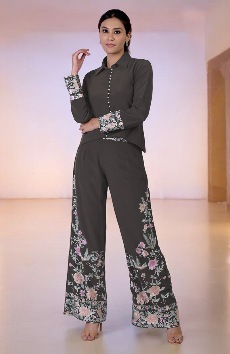 A woman models a dark gray Parsi Gara embroidered co-ord set with floral patterns.