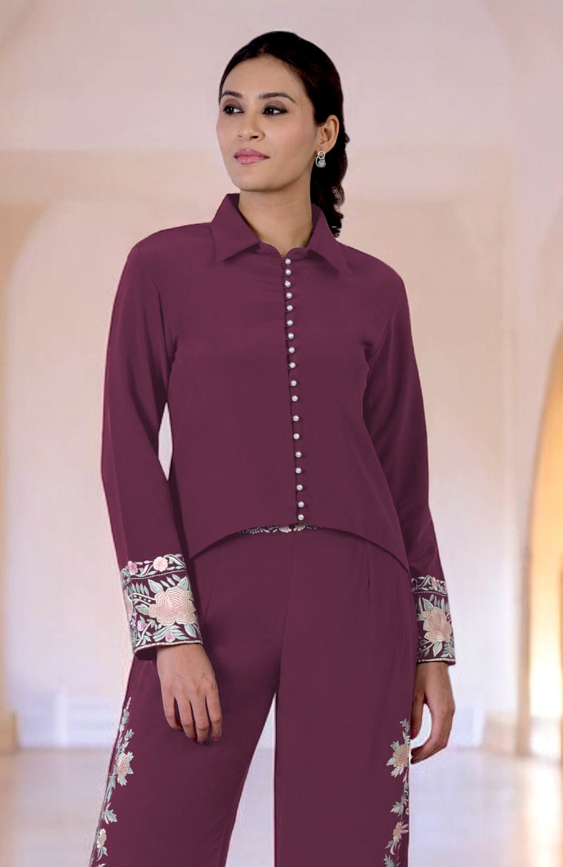 A woman models a maroon Parsi Gara embroidered co-ord set with white buttons.