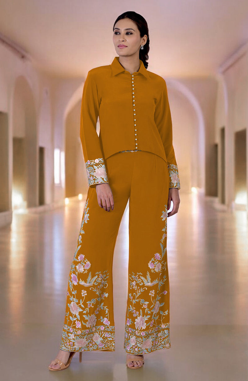 A woman models a yam Parsi Gara embroidered co-ord set with a high-low top and pants.