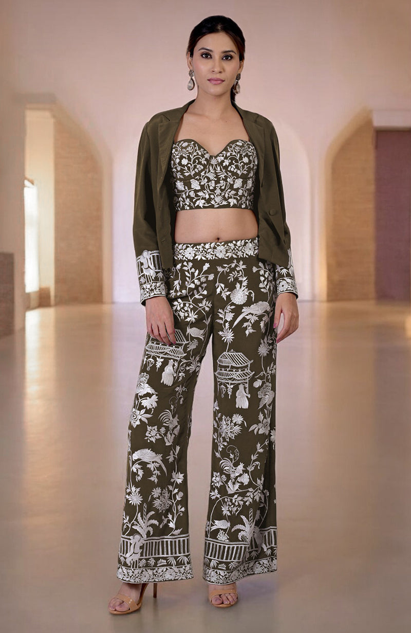 A woman models a dark green Parsi Gara embroidered co-ord set with a jacket.