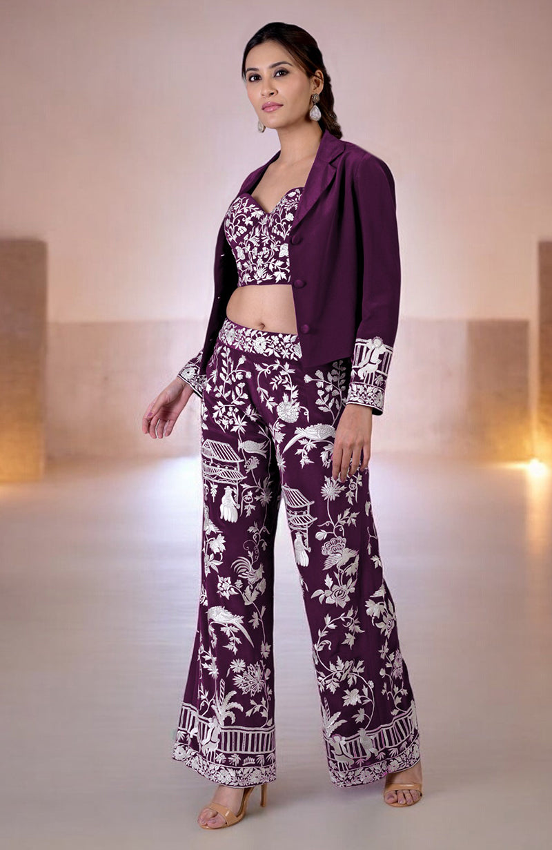 A woman models a ruby wine Parsi Gara embroidered co-ord set with a jacket.