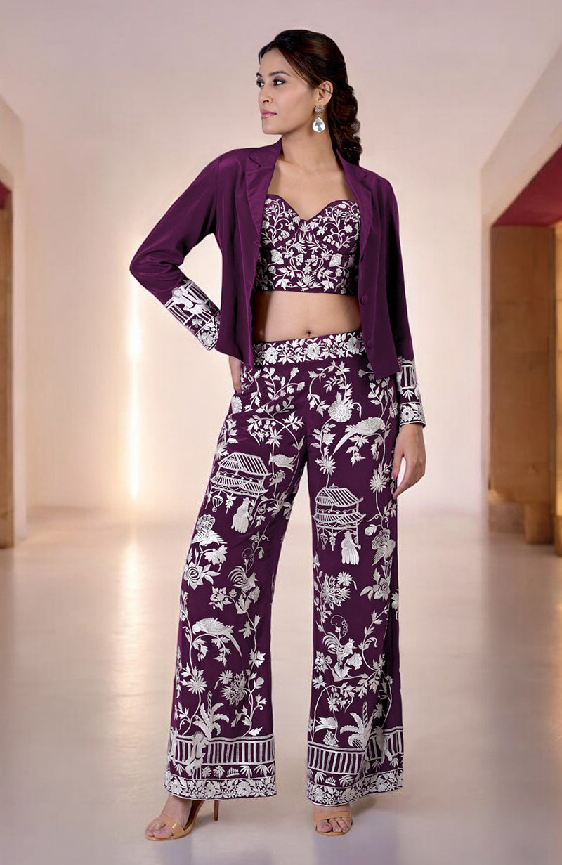 A woman models a plum Parsi Gara embroidered co-ord set with a jacket, corset, and pants.