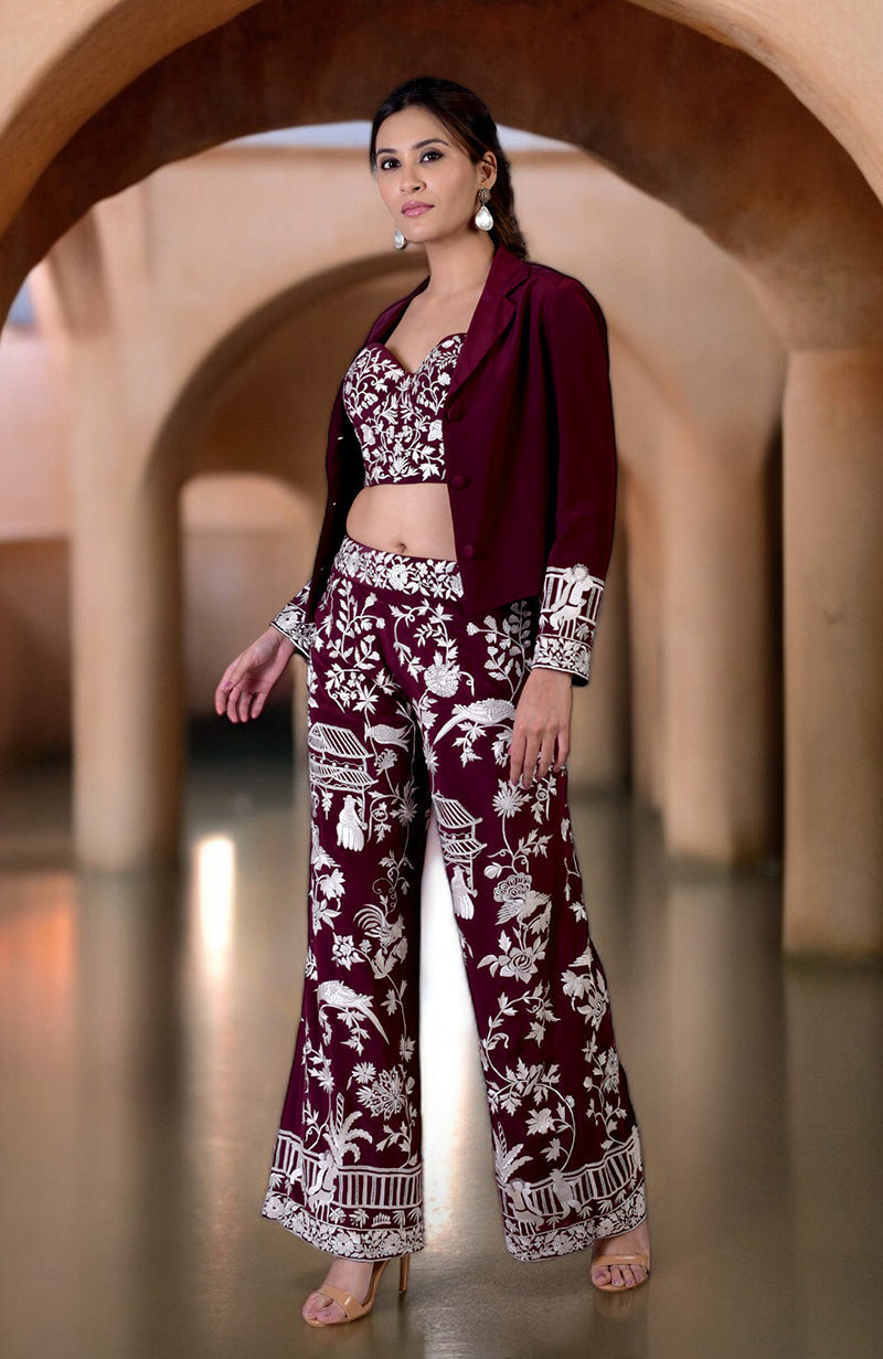 A woman models a ruby wine Parsi Gara embroidered co-ord set with a jacket.