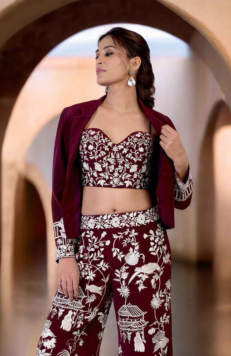 A woman models a ruby wine Parsi Gara embroidered co-ord set with a jacket.