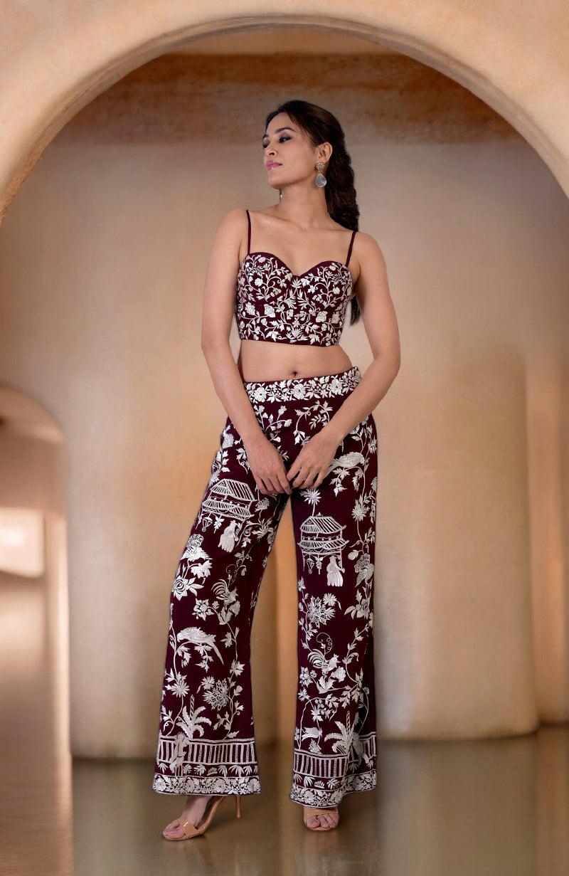 A woman models a ruby wine Parsi Gara embroidered co-ord set with a corset and pants.