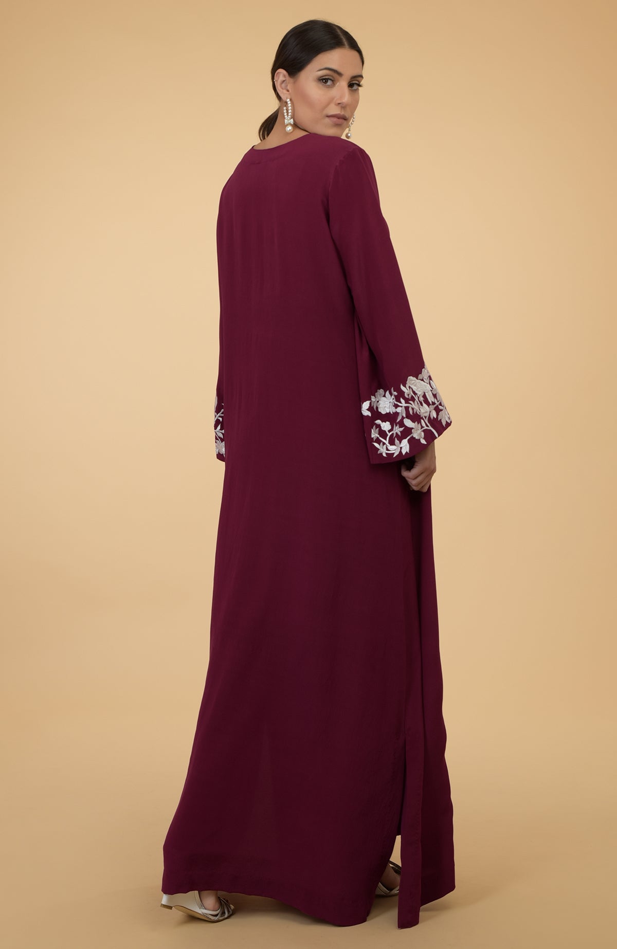Burgundy kaftan with ivory floral and bird embroidery on the sleeves.