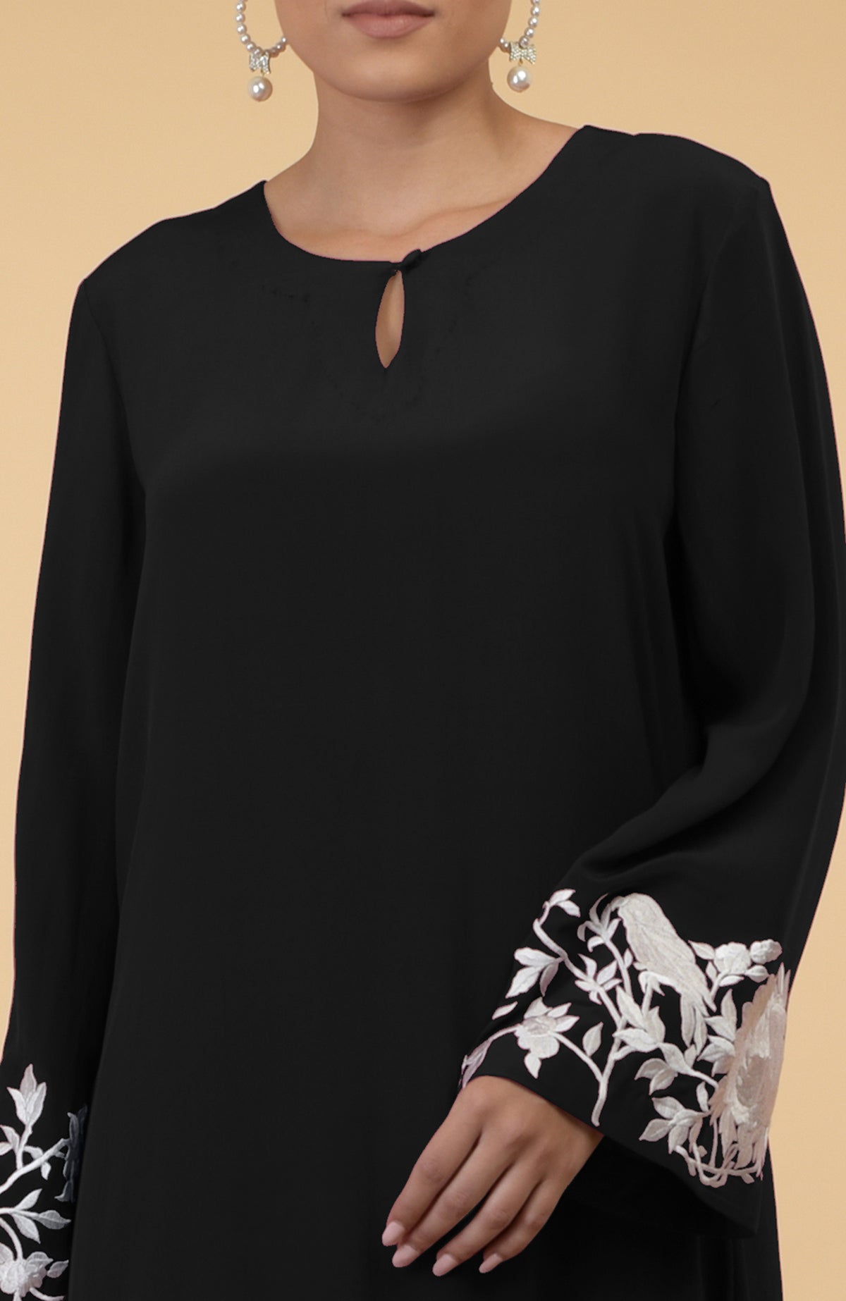 Black silk crepe kaftan with ivory floral and bird embroidery on the sleeves.