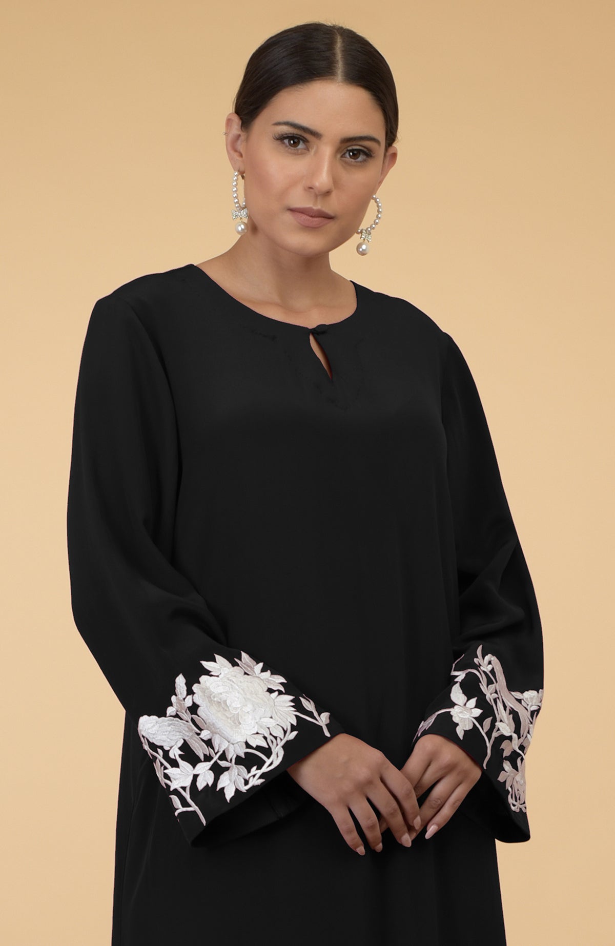 Black silk crepe kaftan with ivory floral and bird embroidery on the sleeves.