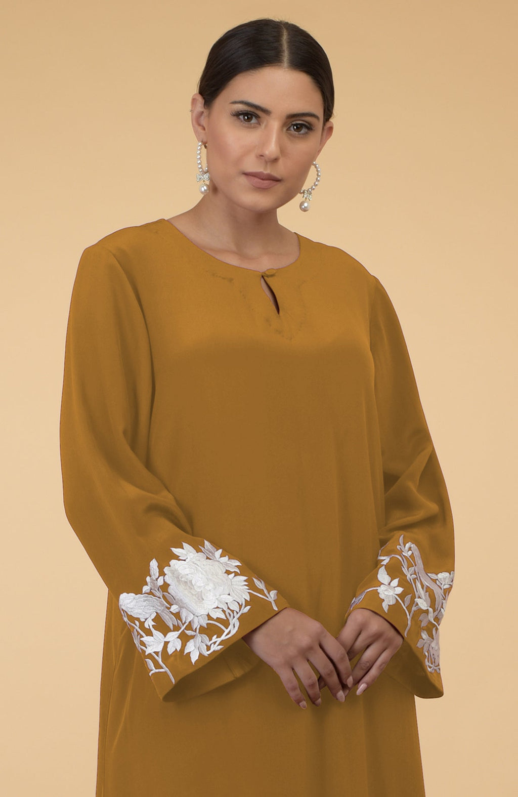 Muted mustard kaftan with floral and bird embroidery on the sleeves.