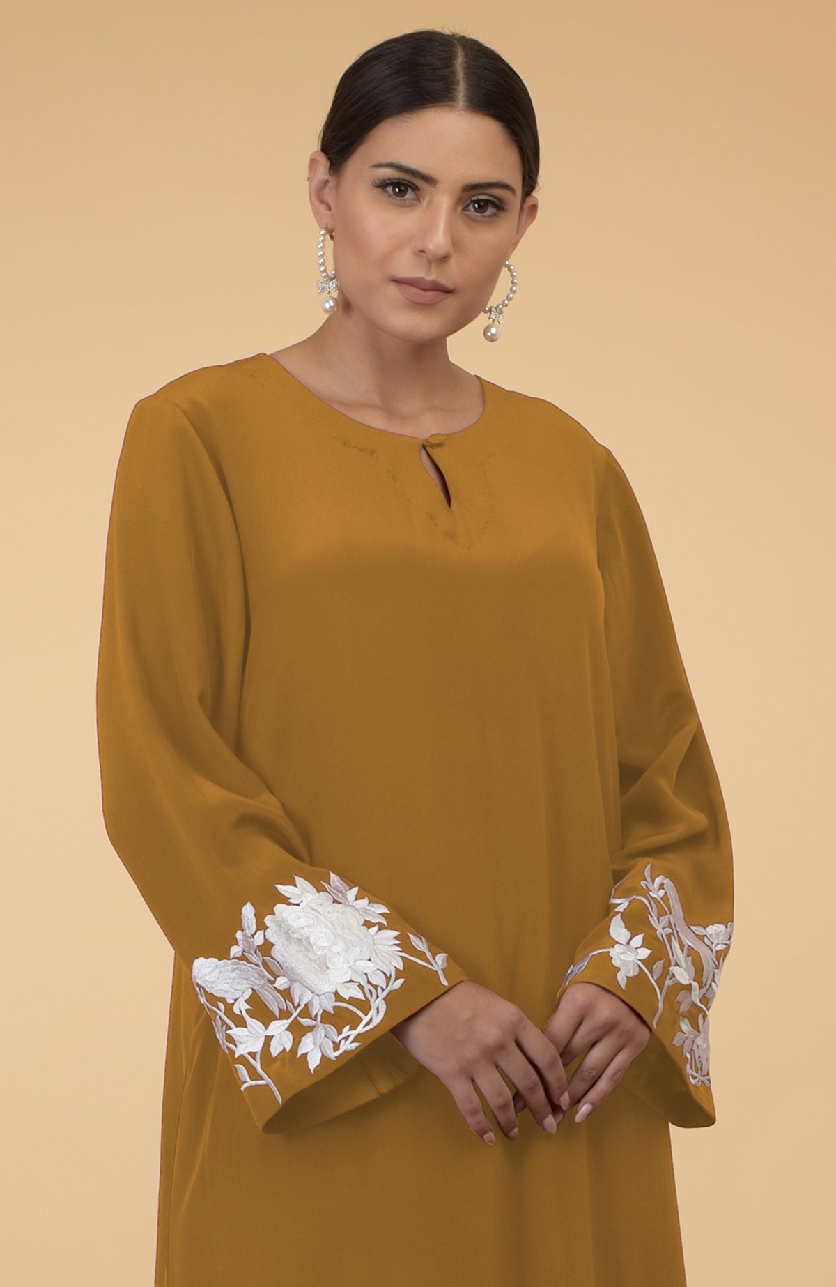 Muted mustard kaftan with floral and bird embroidery on the sleeves.