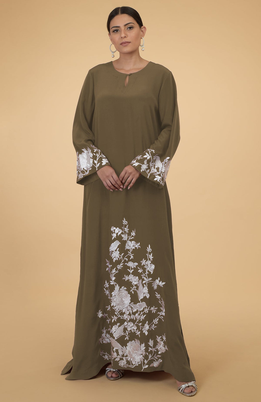 An olive kaftan with white floral and bird embroidery on the sleeves and lower front.