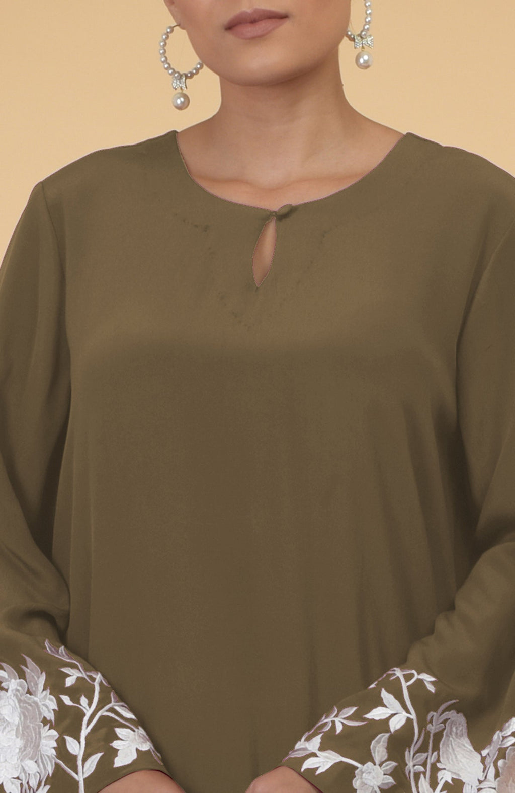 Olive kaftan with a keyhole neckline and white floral and bird embroidery on the sleeves.