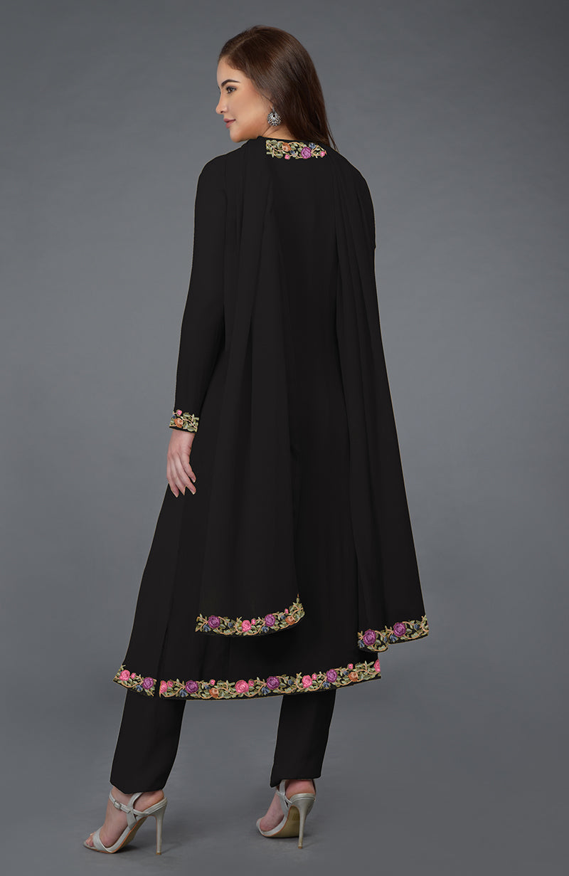 Woman in a black Parsi Gara embroidered overlay suit with floral details.