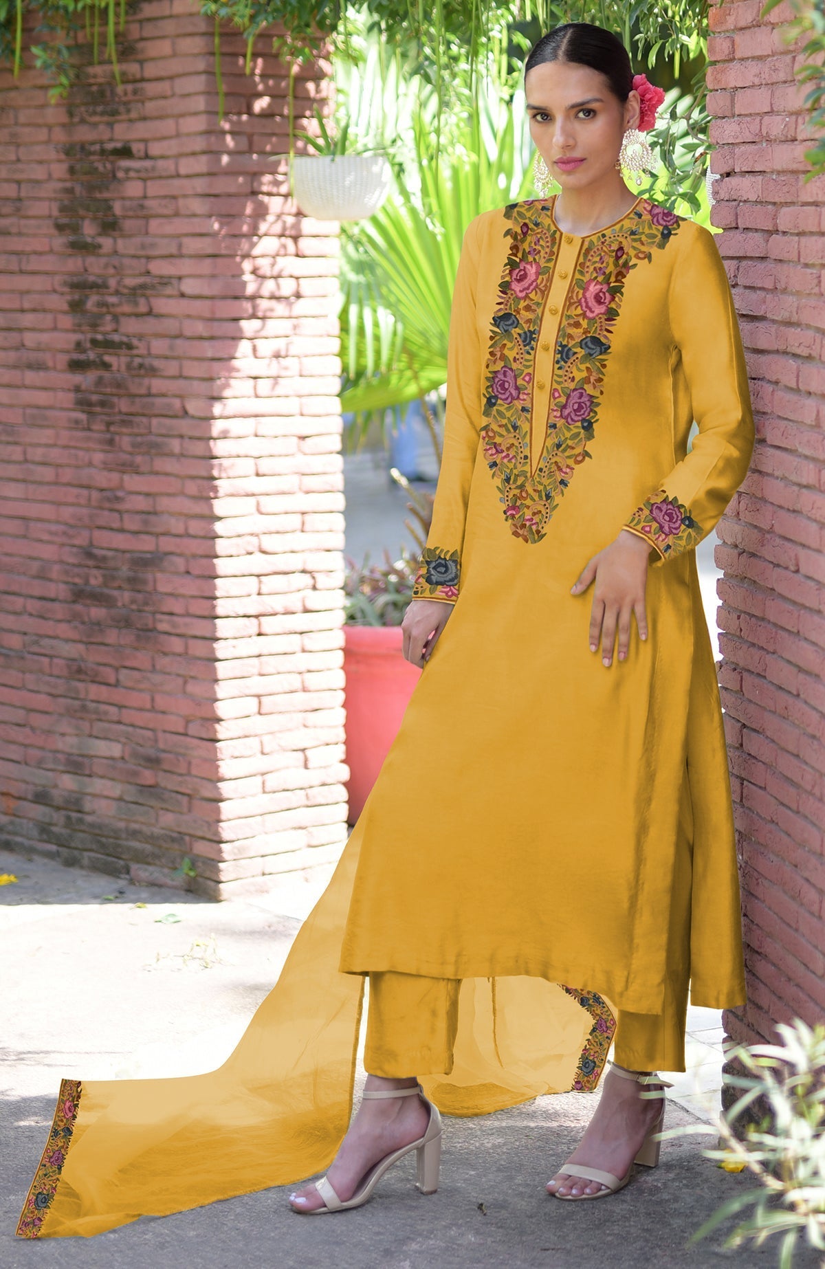 A woman models a calendula yellow Parsi Gara embroidered kurta set with a matching dupatta.