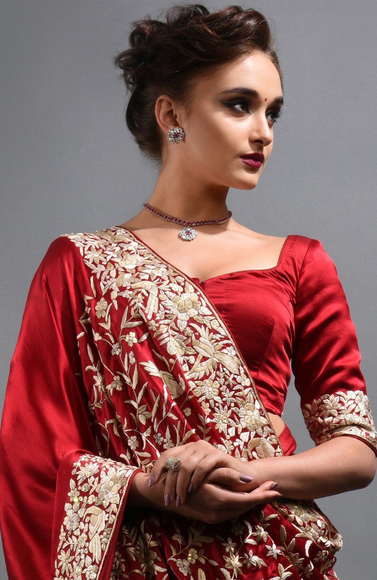 Red-beige Parsi Gara hand-embroidered saree with a matching blouse and jewelry.