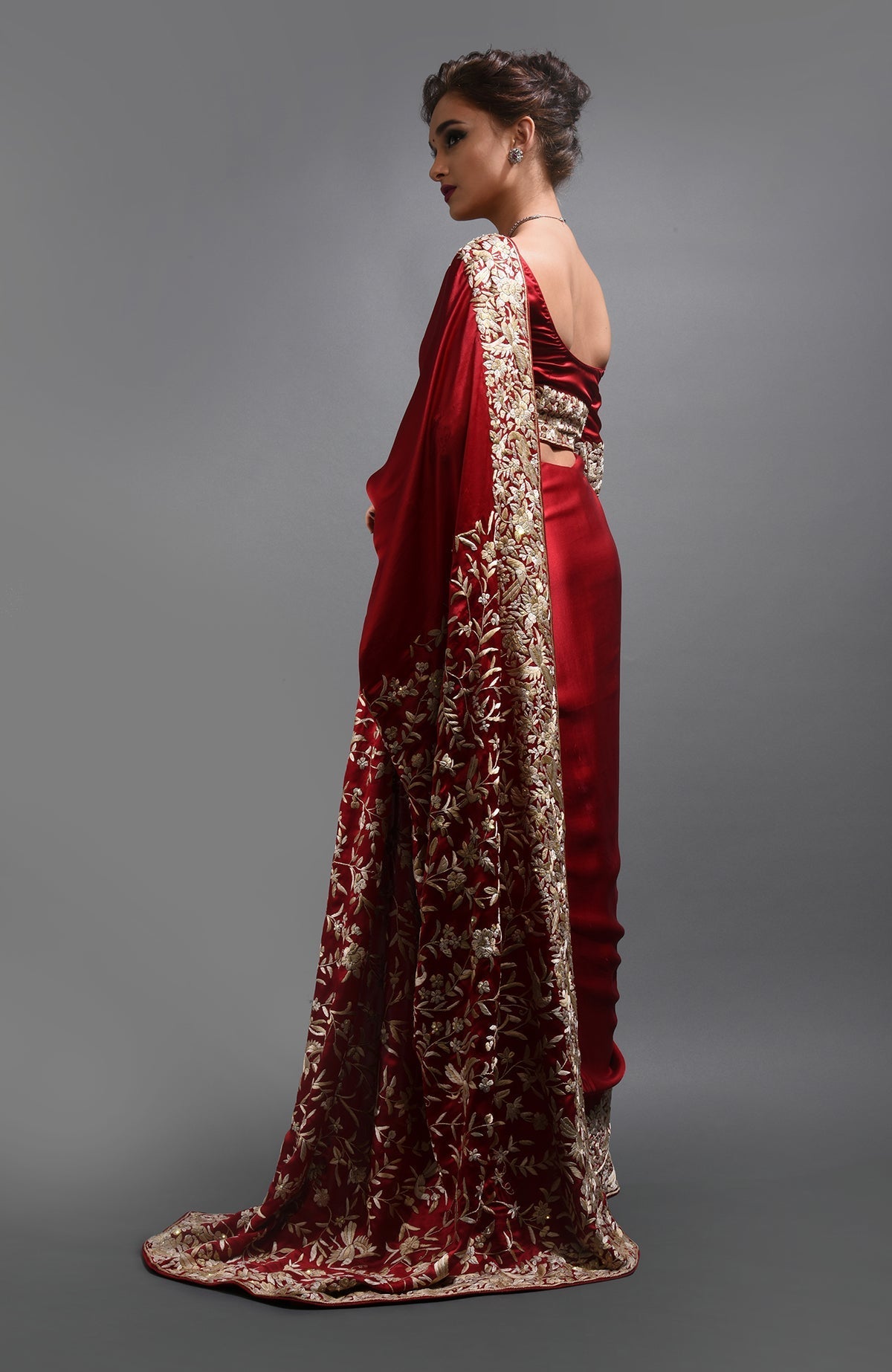 A woman models a red Parsi Gara hand-embroidered saree with beige floral and bird patterns.