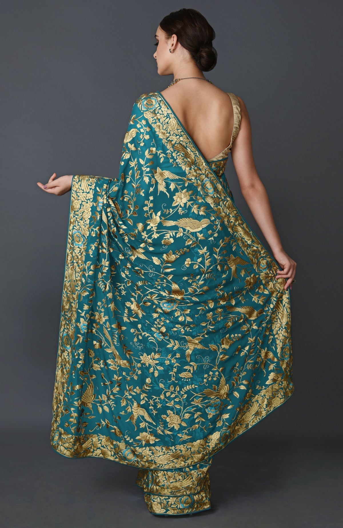 Teal blue georgette saree with beige Parsi Gara bird and floral hand embroidery and matching blouse piece.