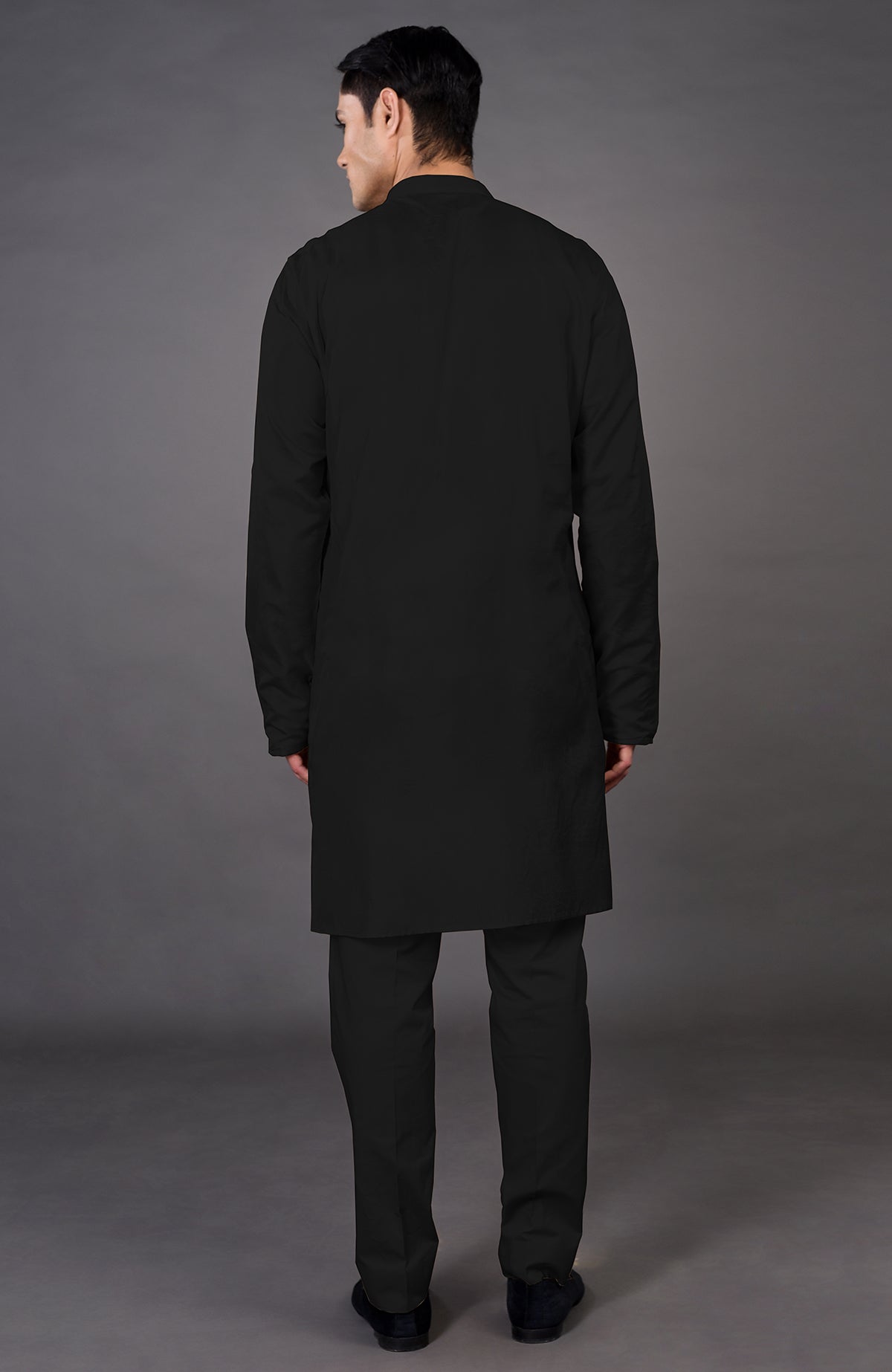 Rear view of a man wearing a black jacket and matching pants.