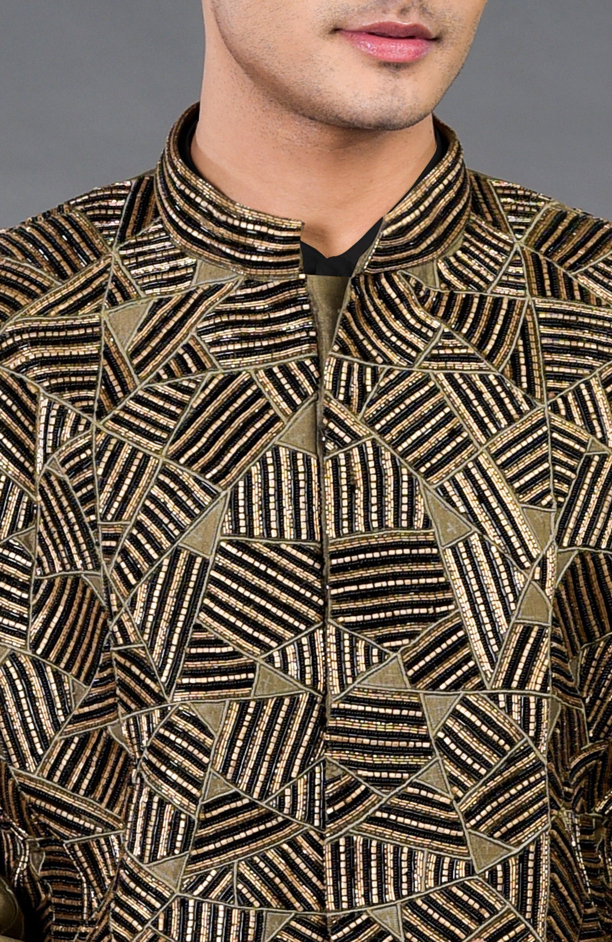 An olive hand-embroidered jacket set with black and gold abstract patterns.
