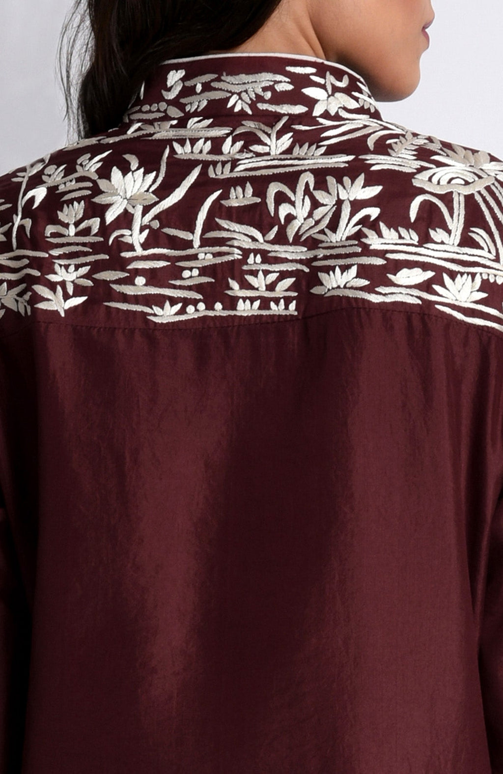 Back of a maroon Parsi Gara embroidered jacket with ivory floral patterns.
