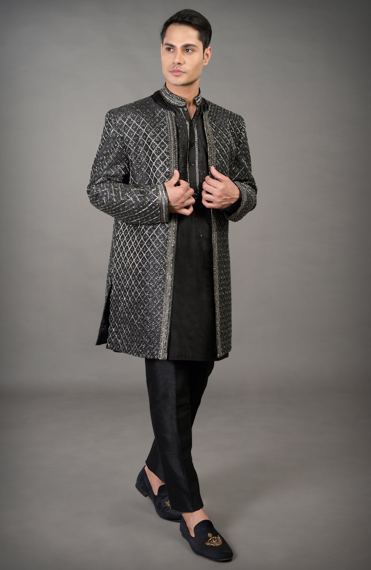 Black hand-embroidered jacket set with a kurta and pants on a male model.