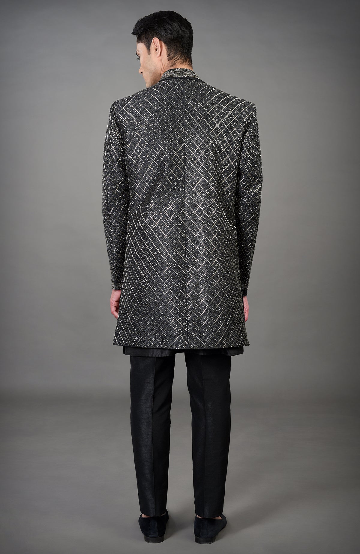 A man from behind wearing a black hand-embroidered jacket set.