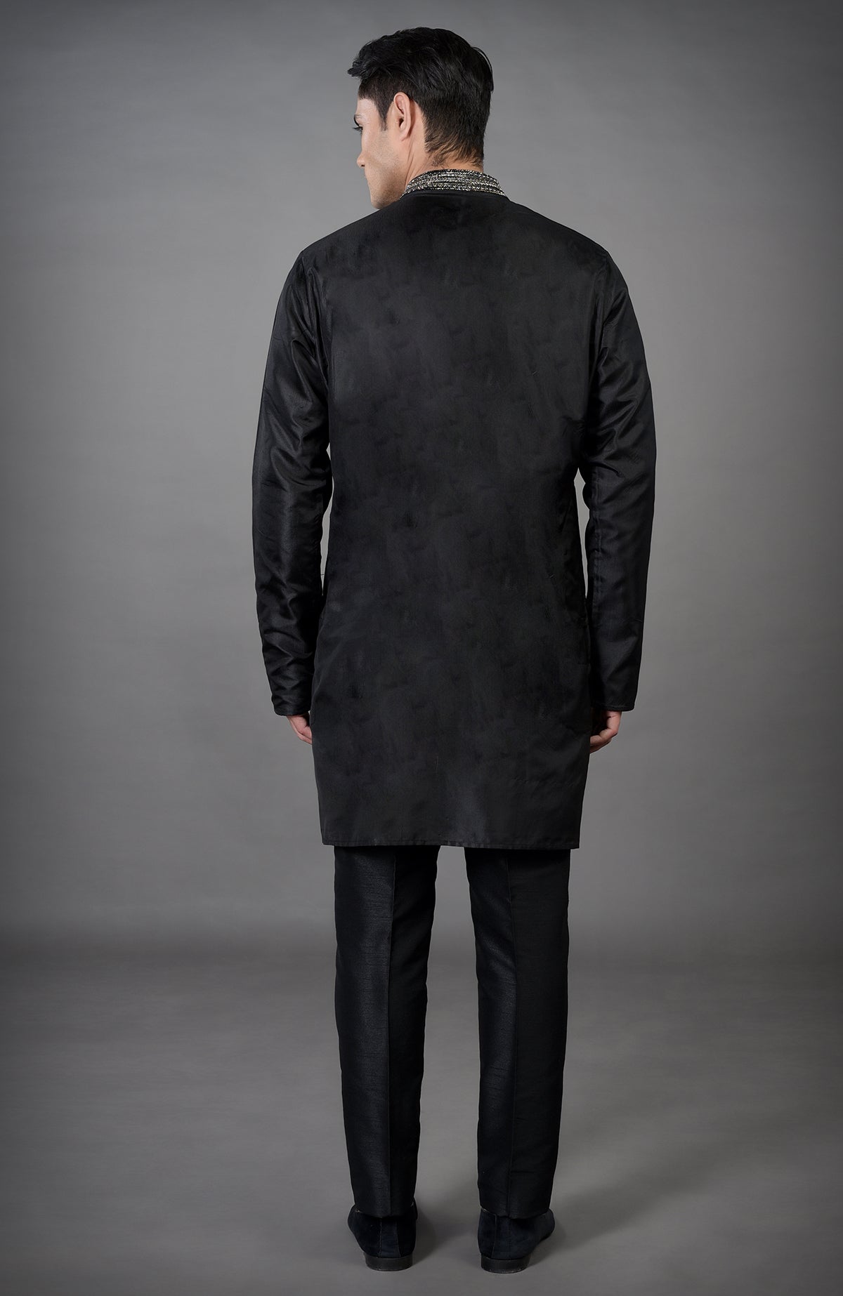 A man from behind wears a black hand-embroidered jacket set.