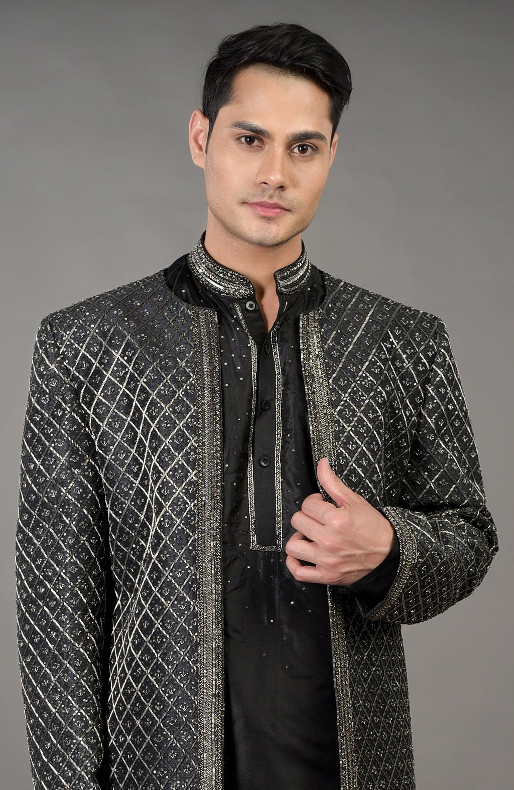 A man models a black hand-embroidered jacket set with a kurta and pants.